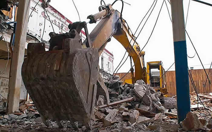 Image of a backhoe breaking down a building